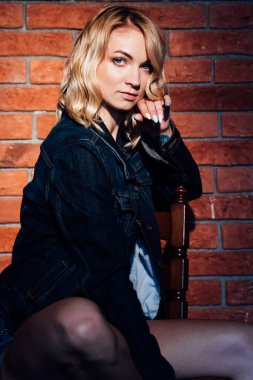 Güzel sarışın kadın tuğla duvara yaslanmış.