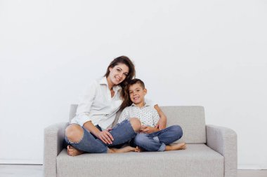 Anne ve oğul, gri bir kanepede ev kıyafetleri içinde.