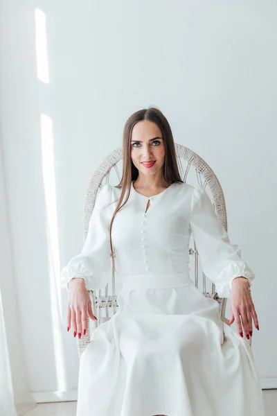 Портрет женщины в светлом летнем платье на белом стуле — стоковое фото