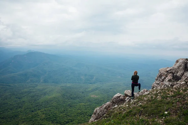 Woman traveler looks at the beautiful landscape from the top of the mountain — Stock Photo, Image