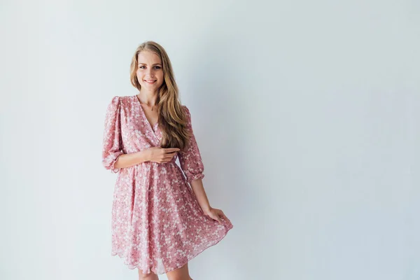 Beautiful blonde woman in a summer dress in a white room — Stock Photo, Image