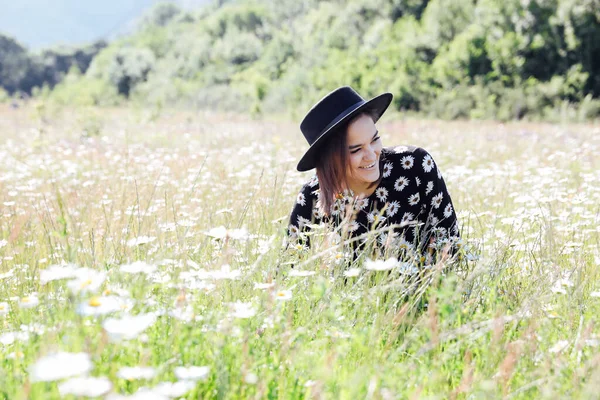 Güzel bir kadın papatya çiçekleriyle tarlada yürüyor.