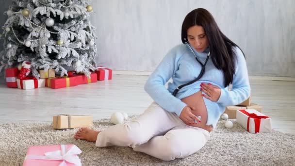 Schöne Schwangere wartet auf Geburt am Weihnachtsbaum — Stockvideo