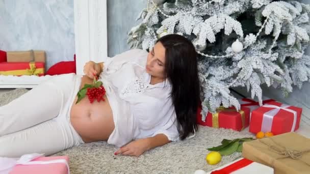 Gyönyörű terhes nő ajándékokkal a karácsonyfa újév — Stock videók