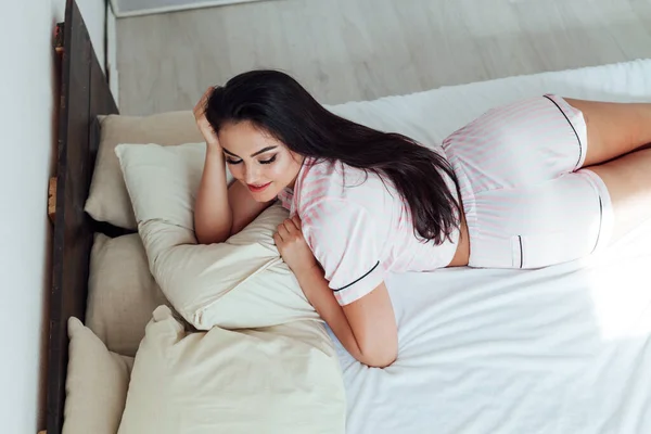 Μελαχρινή γυναίκα με ροζ πιτζάμες στην κρεβατοκάμαρα στο κρεβάτι — Φωτογραφία Αρχείου