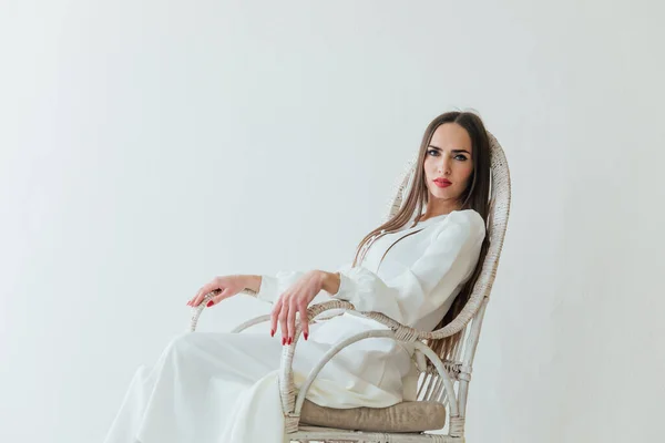 Portrait of a woman in a light summer dress on a white chair — Stock Photo, Image