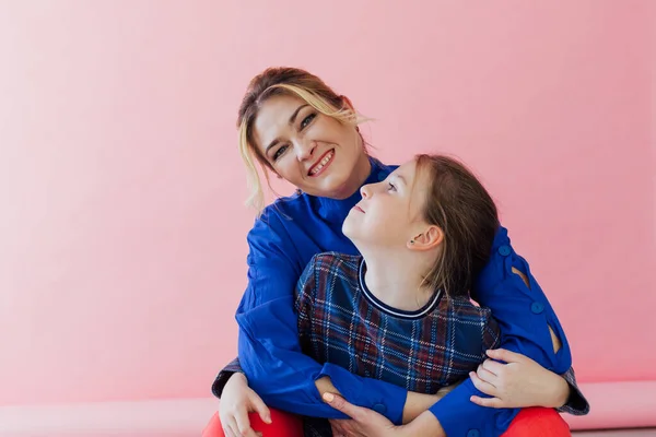 Mother and daughter embrace smiling against a pink background — 图库照片