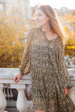 Güzel sarışın kadın sonbahar şehrinin sokaklarında yürüyor.