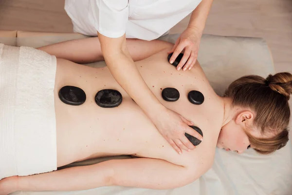 Massage therapist makes a therapeutic massage with stones Royalty Free Stock Images