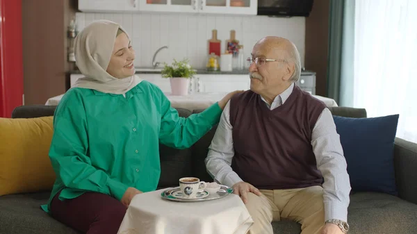 Happy loving old man drinking Turkish coffee in traditional cup. Old man having a good time chatting with his visiting daughter while drinking Turkish coffee.Happy father and daughter portrait.