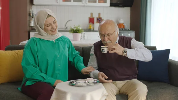 Happy loving old man drinking Turkish coffee in traditional cup. Old man having a good time chatting with his visiting daughter while drinking Turkish coffee.Happy father and daughter portrait.
