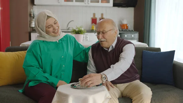 Happy loving old man drinking Turkish coffee in traditional cup. Old man having a good time chatting with his visiting daughter while drinking Turkish coffee.Happy father and daughter portrait.