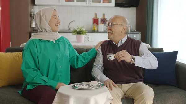 Happy loving old man drinking Turkish coffee in traditional cup. Old man having a good time chatting with his visiting daughter while drinking Turkish coffee.Happy father and daughter portrait.