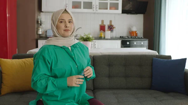 Young woman in hijab looking at empty advertising space to the left of the camera.Portrait of woman looking to the left of the screen while sitting on the sofa at home.