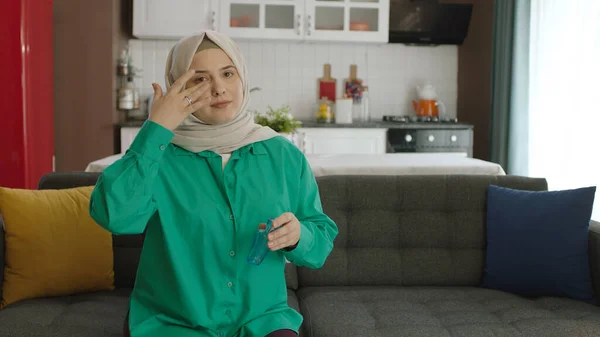 Young woman in hijab looking at empty advertising space to the left of the camera.Portrait of woman looking to the left of the screen while sitting on the sofa at home.