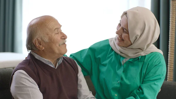 The young woman in a hijab is happy to see her father coming to visit. The old man and his daughter are smiling happily at the camera. Portrait of happy father and daughter.