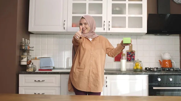 Mujer Hijab Sosteniendo Algo Verde Cocina Mostrando Producto Sonriendo Presentando — Foto de Stock