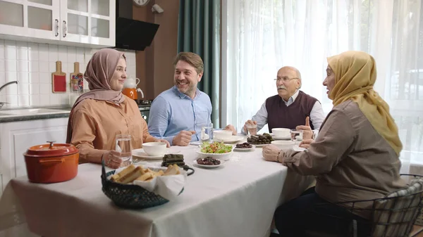 Happy Muslim family having iftar dinner together in the kitchen. A Muslim Turkish family breaks their fast at the iftar table. Iftar is the evening meal at which Muslims