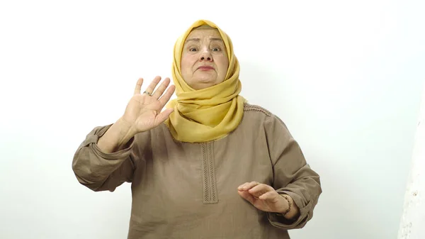 I don\'t want to watch! Old lady in a beautiful turban closing her eyes and making a gesture. Confused and shy to look at the embarrassing content. Indoor studio shot isolated on white.