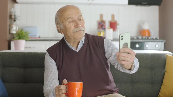 70年代快乐的男性用户一边上网一边喝咖啡一边打电话 一边看着屏幕坐在沙发上 自私自利 老爷爷在学习使用现代技术 — 图库照片