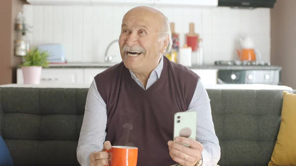 Velho Assistindo Vídeo Engraçado Seu Smartphone Enquanto Bebe Café Casa — Fotografia de Stock