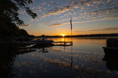 Sunburst sunrise over glassy lake with perfect reflection of clouds