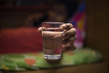 Close up image, focus on Indian friendly boy holding glass of still clean water.selective focus in hand and glass, daily enough body hydration refreshment concept