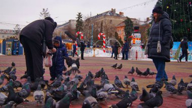 Çocuklar tiyatro meydanında güvercinleri besler. Ternopil Meydanı. Ternopil Peace. Ternopil güvercinleri. Ternopil 'in merkez meydanında güvercinler. Şehirdeki insanların ve vahşi yaşamın etkileşimi. Ternopil 'in merkezinde güvercinler.