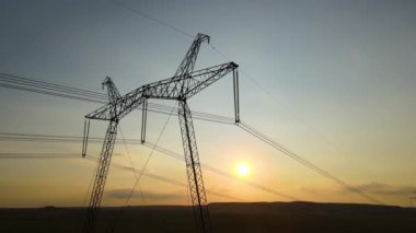 Gün batımında elektrik hatları olan yüksek voltaj kuleleri..
