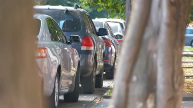 Sokak kenarında park halindeki arabalarla şehir trafiği.