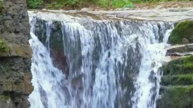 Yazın yağmur ormanlarında kayalık kayalıklardan dökülen beyaz köpüklü suyla dağ nehrindeki muhteşem şelale manzarası..