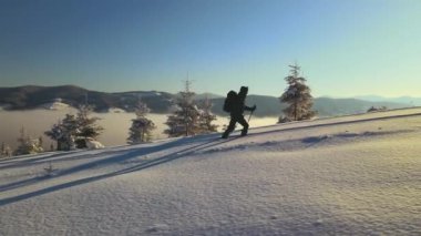 Soğuk kış gününde dağ yamacında yürüyüş yapan sırt çantalı adamın hava manzarası..