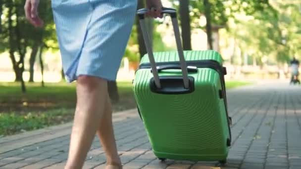 夏の日に緑のスーツケースと街の歩道を歩く若い女性の閉鎖 旅行と休暇のコンセプト — ストック動画