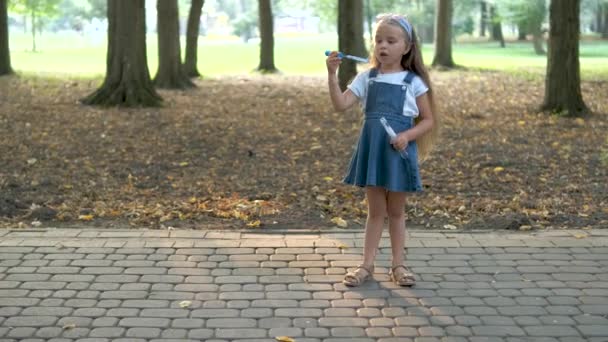 Malá šťastná holčička fouká mýdlové bubliny venku v Green Parku. Koncept venkovních letních aktivit.