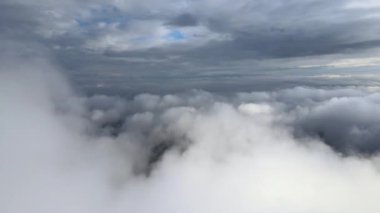 Dünya 'nın yüksek irtifasında, yağmur fırtınasından önce oluşan kabarık kümülüs bulutlarıyla kaplı uçak penceresinden hava görüntüsü.