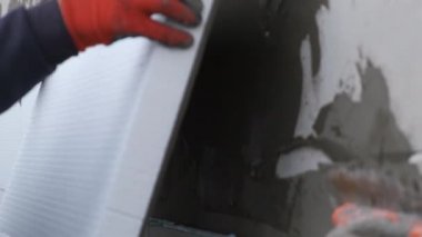 İnşaat işçisi termal koruma için evin ön cephesine köpük yalıtım çarşafları yerleştiriyor..
