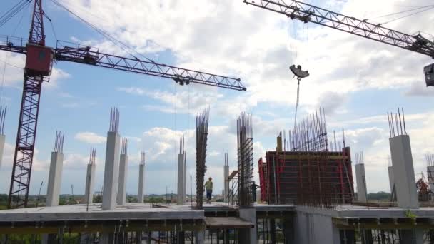 Turmdrehkräne und Arbeiter an einem hohen Betonwohnhaus im Bau. Immobilienentwicklungskonzept. — Stockvideo