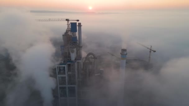 Vue aérienne de la cimenterie avec structure en béton élevé et grue à tour sur le site de production industrielle le matin brumeux. Fabrication et concept d'industrie mondiale. — Video