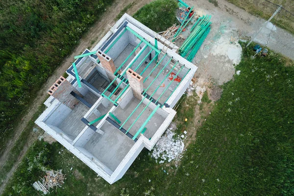 Havalandırılmış hafif beton duvarları ve inşaat halindeki ahşap çatı kirişleri olan bitmemiş özel evin havadan görüntüsü..