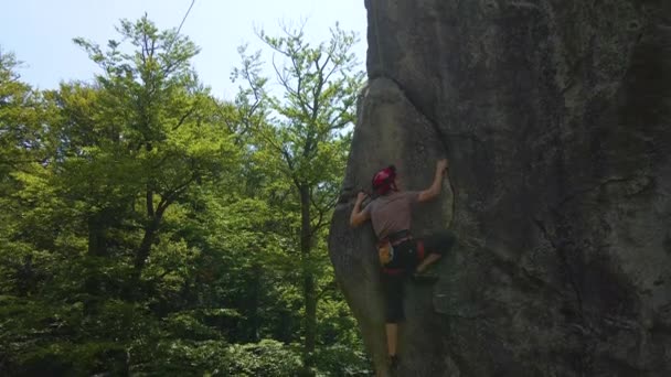 Nuori mies kiipeää kalliovuoren jyrkkää seinää pitkin. Mieskiipeilijä voittaa haastavan reitin. Äärimmäisen urheilun käsite — kuvapankkivideo