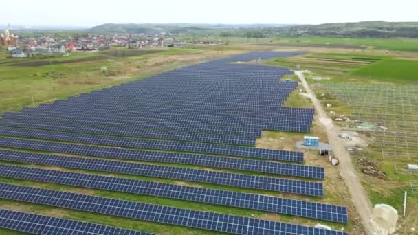 Vista aérea de la construcción de grandes plantas de energía eléctrica con muchas filas de paneles solares en el marco de metal para producir energía eléctrica ecológica limpia. Desarrollo de fuentes de electricidad renovables — Vídeo de stock
