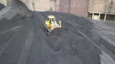Buldozer çekici termoelektrik santralinin ikmal sahasında siyah kömür topluyor.