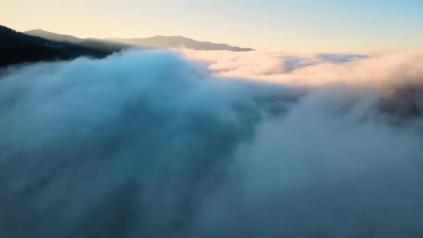 Veduta aerea del paesaggio sopra nebbia veloce nuvole in movimento che coprono colline di montagna al tramonto. — Video Stock