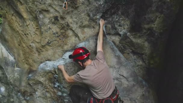 Odhodlaný horolezec šplhá po příkré stěně skalnaté hory. Sportovec překonává obtížnou cestu. Zapojení do extrémních sportů a horolezectví hobby koncept. — Stock video