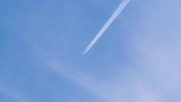 Uzaktaki yolcu uçağı mavi gökyüzünde yüksek irtifada uçarken beyaz bulutlar ardında iz bırakıyor. Hava yolculuğu konsepti. — Stok video