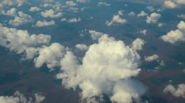 Parlak güneşli bir günde beyaz bulutların uçak penceresinden hava manzarası.