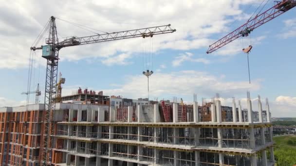 Věžové jeřáby a profesionální pracovníci na vysoké betonové obytné budově ve výstavbě. Koncept developmentu nemovitostí. — Stock video