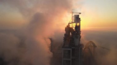 Beton yapılı çimento fabrikasının havadan görünüşü ve sisli bir akşamda endüstriyel üretim alanında kule vinci. Üretim ve küresel sanayi kavramı