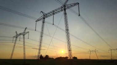 Güneş doğarken elektrik hatları olan yüksek voltajlı kulelerin koyu gölgesi.