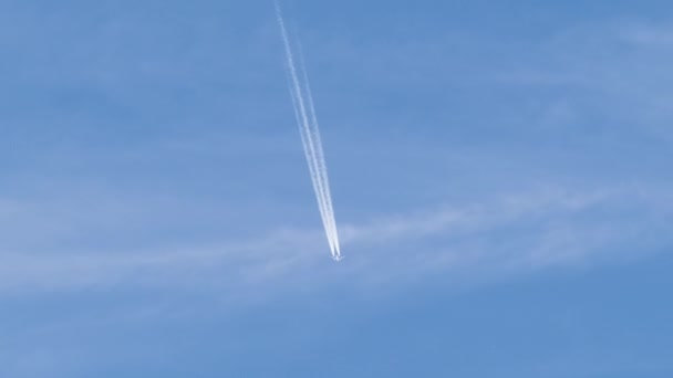 Avião de passageiros distantes voando em alta altitude no céu azul com nuvens brancas deixando vestígios de fumaça de contrail para trás. Conceito de viagem aérea. — Vídeo de Stock